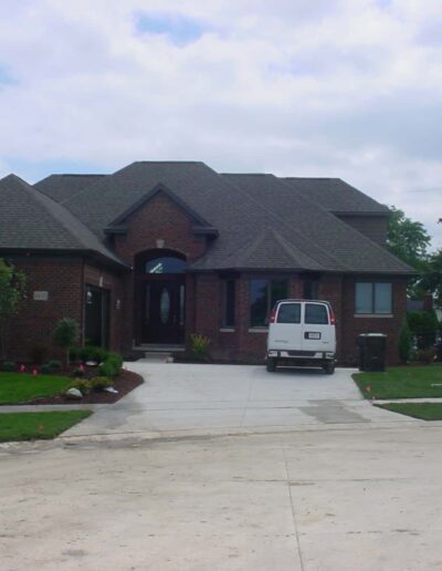Brick suburban home with a white van parked in the driveway under a cloudy sky.